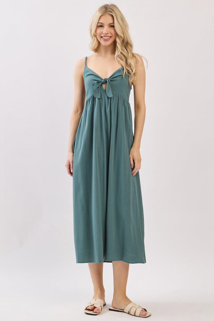 woman wearing a teal maxi dress with a bow tie detail at the bust and spaghetti straps