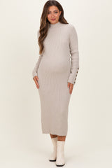 woman wearing a light gray ribbed maternity dress with long sleeves and button details on the cuffs, showing her baby bump