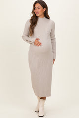 woman wearing a beige ribbed maternity dress with long sleeves and button details, holding her baby bump