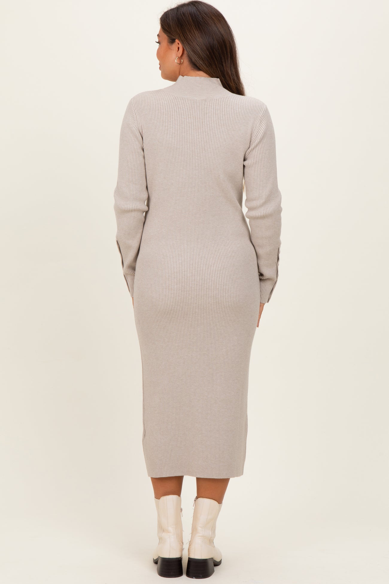 woman wearing a beige ribbed maternity dress with long sleeves and a mid-calf length, showing a fitted silhouette