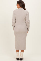 woman wearing a beige ribbed maternity dress with long sleeves and a mid-calf length, showing a fitted silhouette