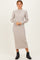 woman wearing a beige ribbed midi dress with long sleeves and button detailing on the cuffs