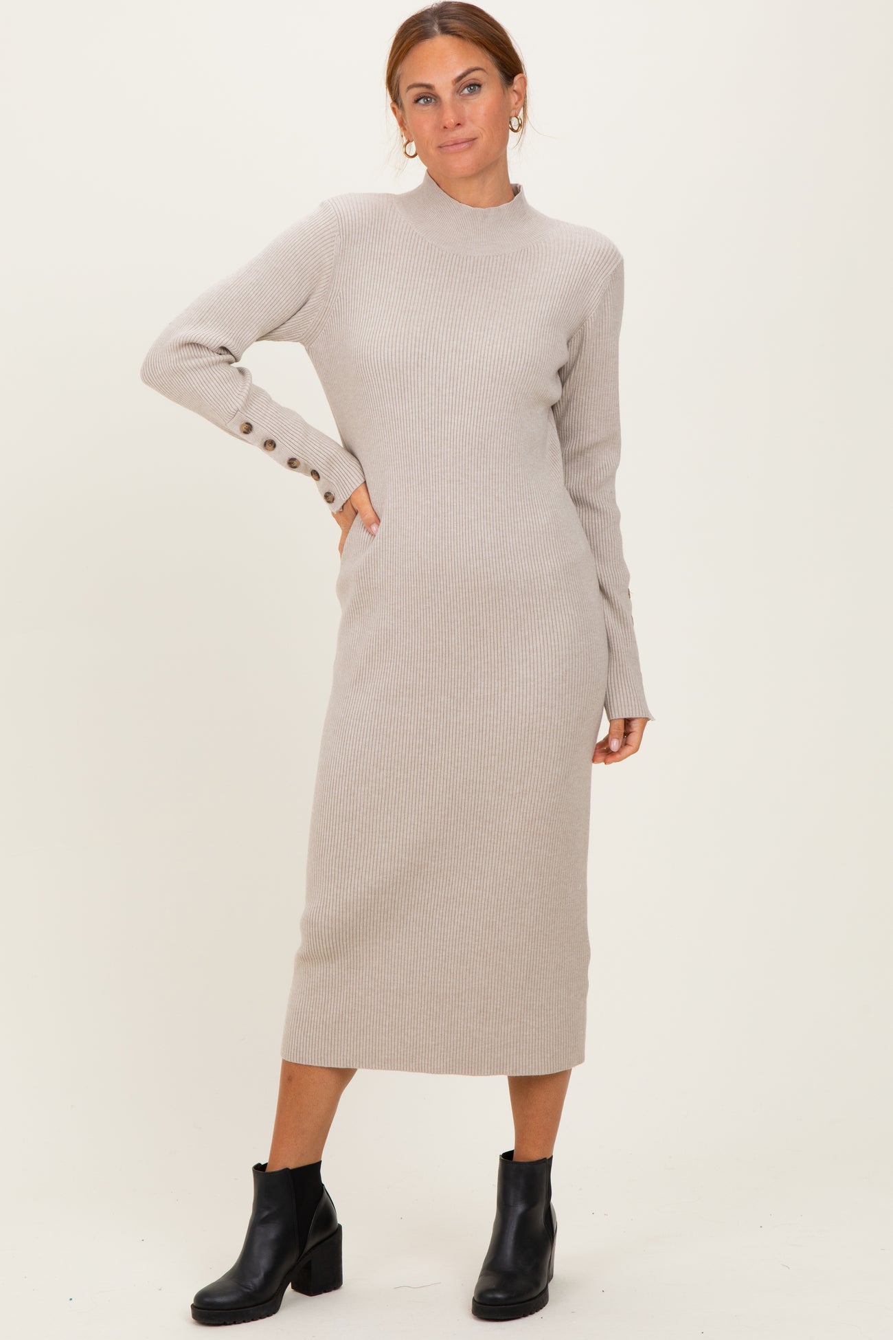 woman wearing a light beige ribbed midi dress with long sleeves and button detail, paired with black ankle boots