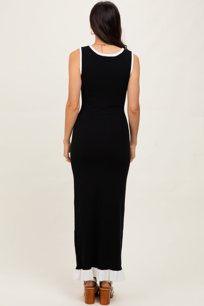 woman wearing a sleeveless black maxi dress with a white trim at the hem and a fitted silhouette