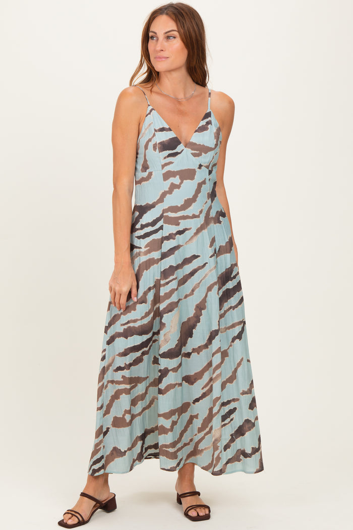woman wearing a light blue maxi dress with a abstract brown and gray pattern and spaghetti straps