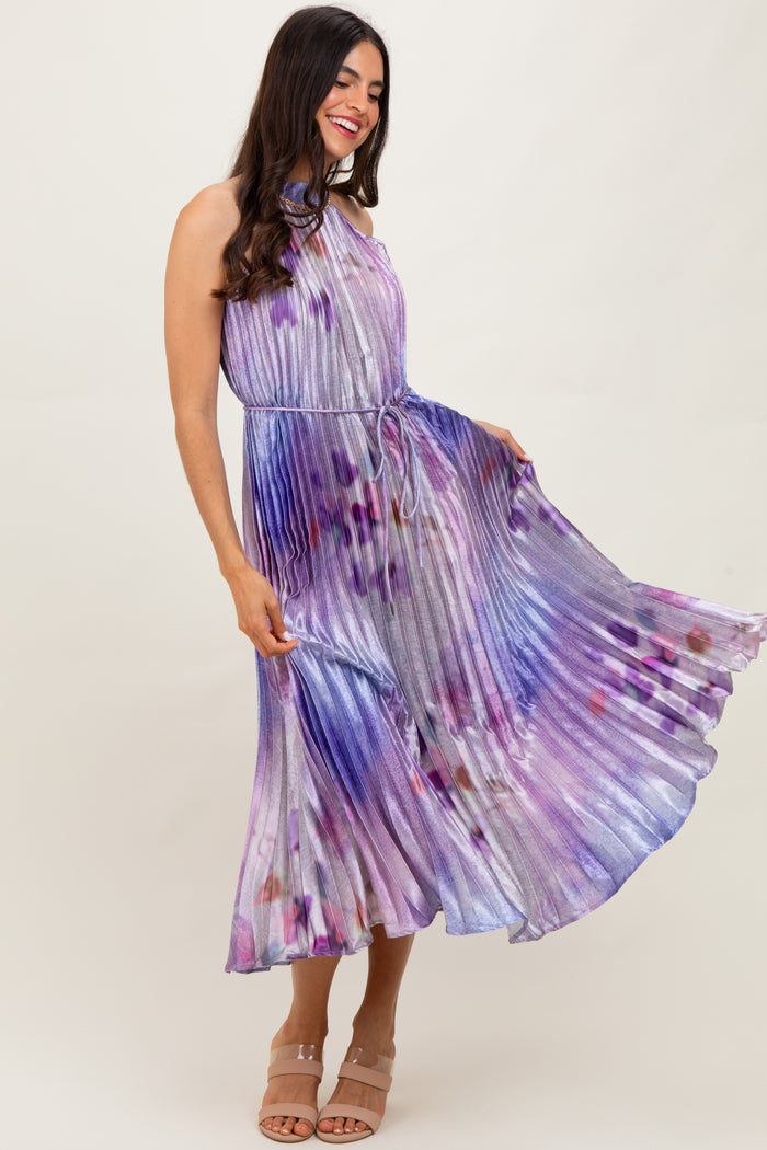 woman wearing a purple and multicolored pleated maxi dress with a halter neck and a waist tie