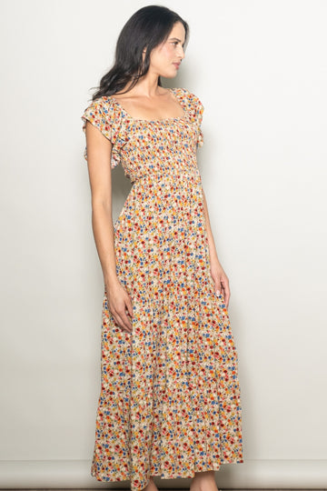woman wearing a floral print maxi dress with flutter sleeves and a smocked bodice