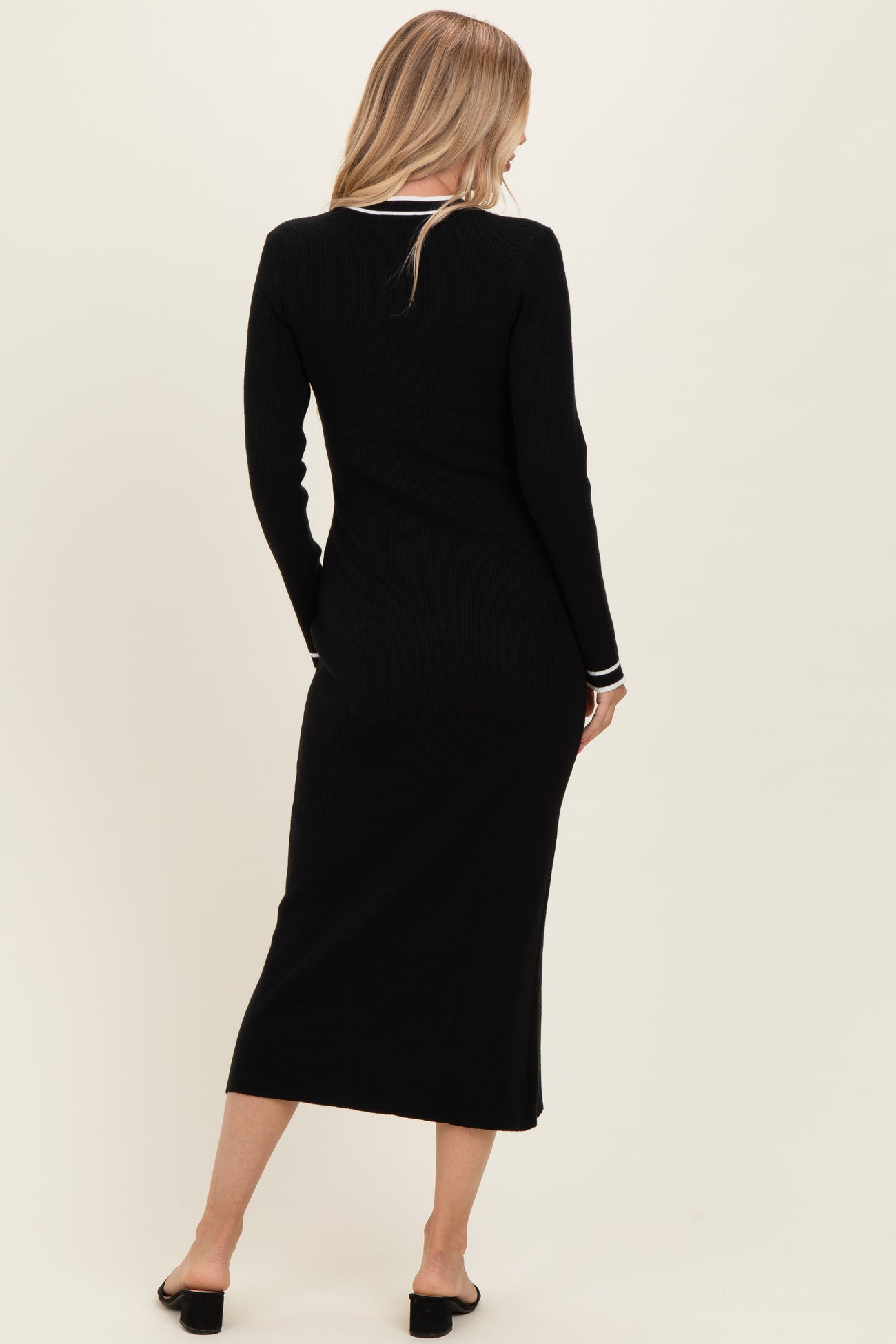 woman wearing a black ribbed midi dress with long sleeves and white trim details, viewed from the back