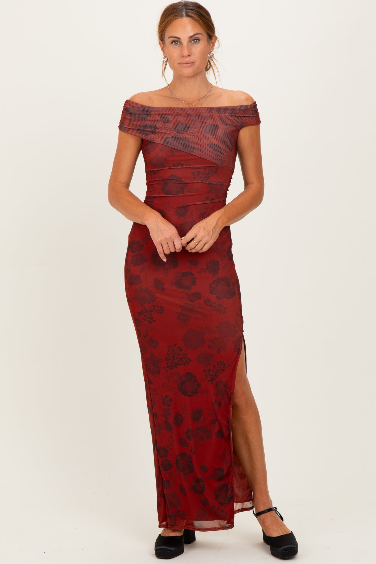 woman wearing a burgundy off-shoulder maxi dress with floral print and a side slit