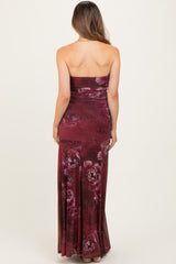 woman wearing a burgundy floral strapless maternity dress with a fitted silhouette and a long flowy skirt