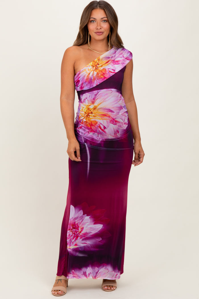 woman wearing a one-shoulder floral maternity dress in purple and pink tones with a fitted silhouette and maxi length