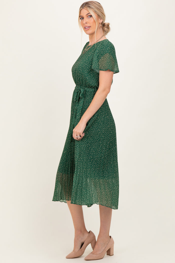 woman wearing a green floral midi dress with short sleeves and a tie waist, styled with beige heels