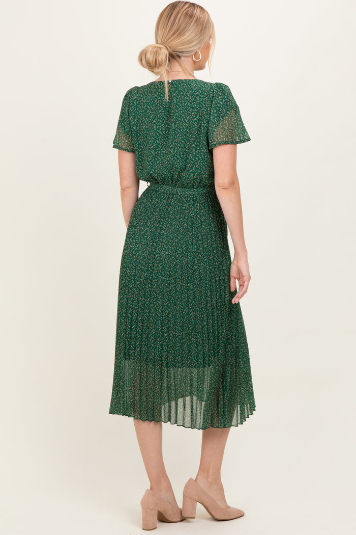 woman wearing a green floral pleated midi dress with short sleeves and a tie waist detail