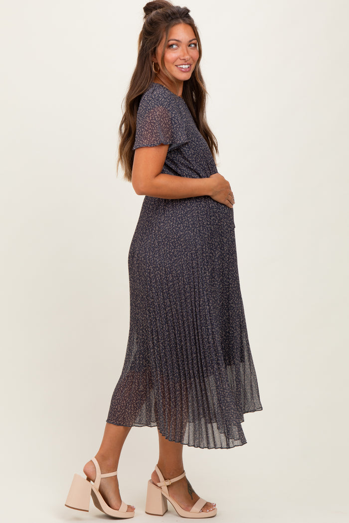 woman wearing a navy floral midi maternity dress with short sleeves and a pleated skirt, showcasing her baby bump