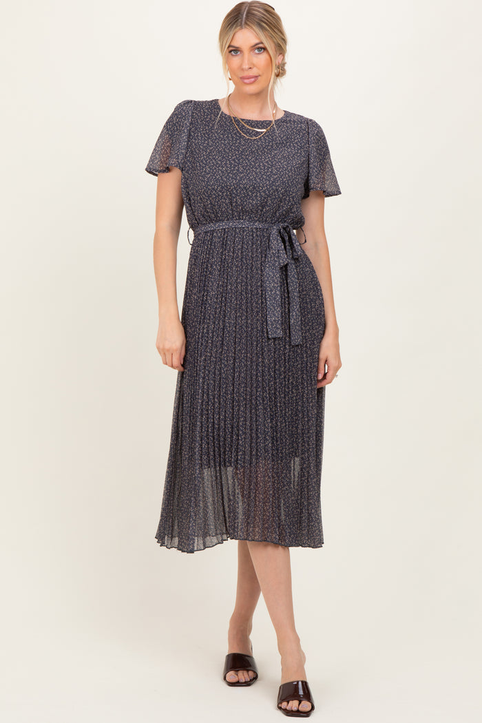 woman wearing a navy blue pleated midi dress with short sleeves and a tied waist belt