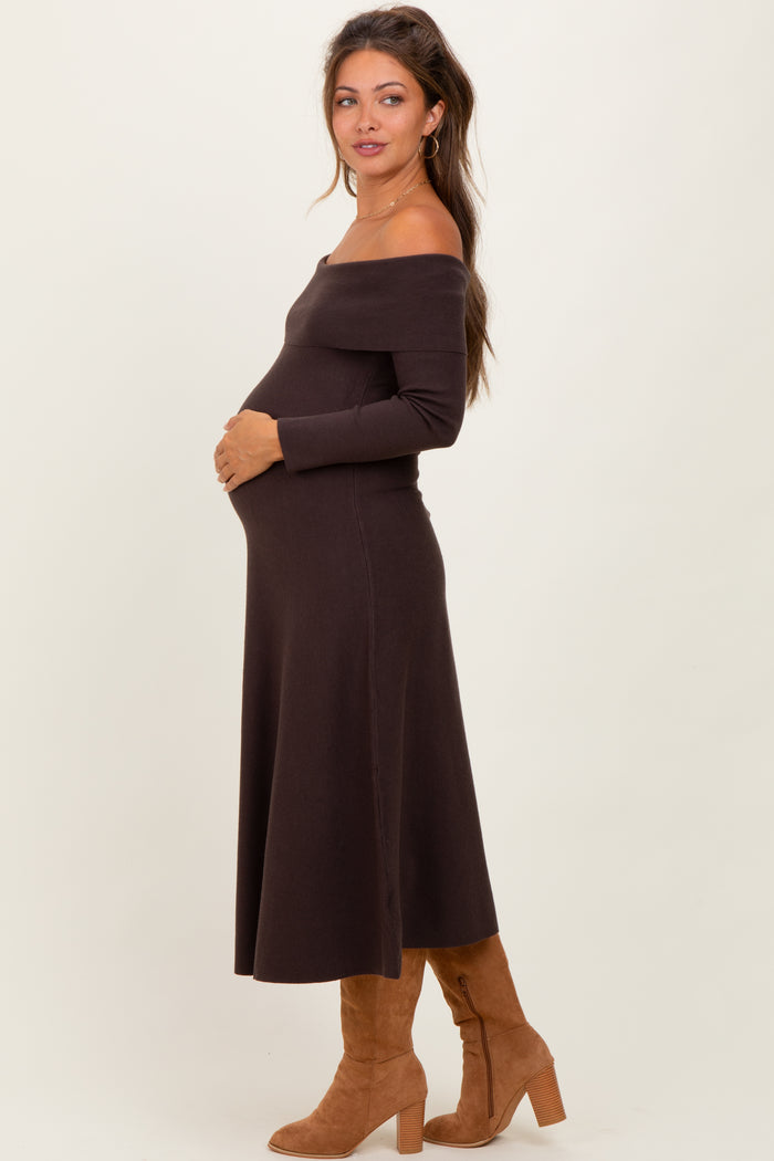 woman wearing a dark brown off-shoulder maternity dress and holding her baby bump