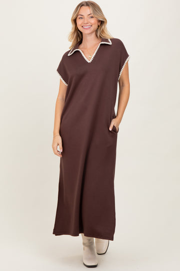 woman wearing a brown maxi dress with a collar and pocket details, standing against a neutral background