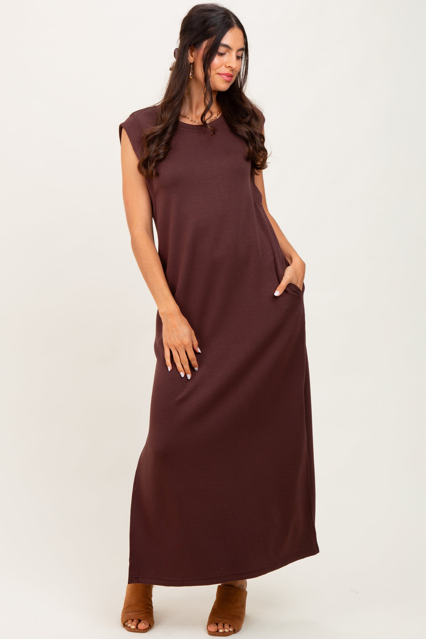 woman wearing a sleeveless brown maxi dress with side pockets and a relaxed fit