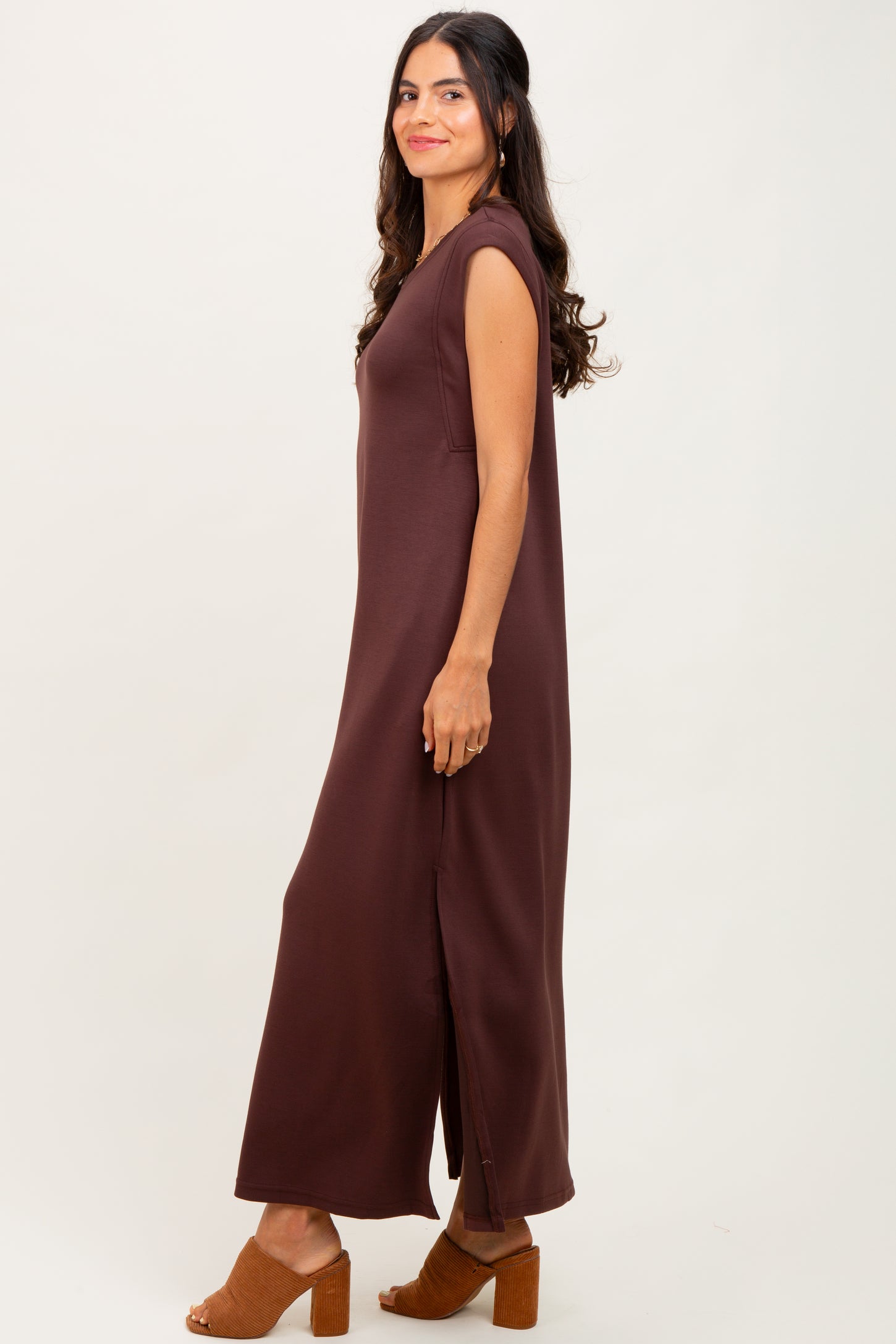 woman wearing a brown sleeveless maxi dress with side slits and styled with brown block heel sandals