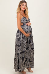woman wearing a black and white patterned maternity maxi dress, cradling her baby bump