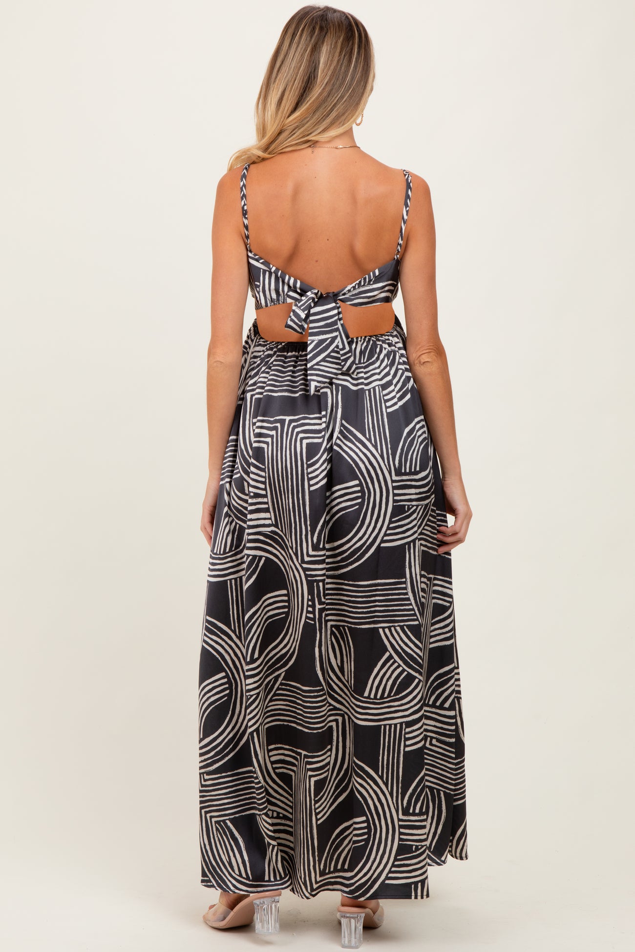 woman wearing a black and white patterned maternity maxi dress with an open back and tie details