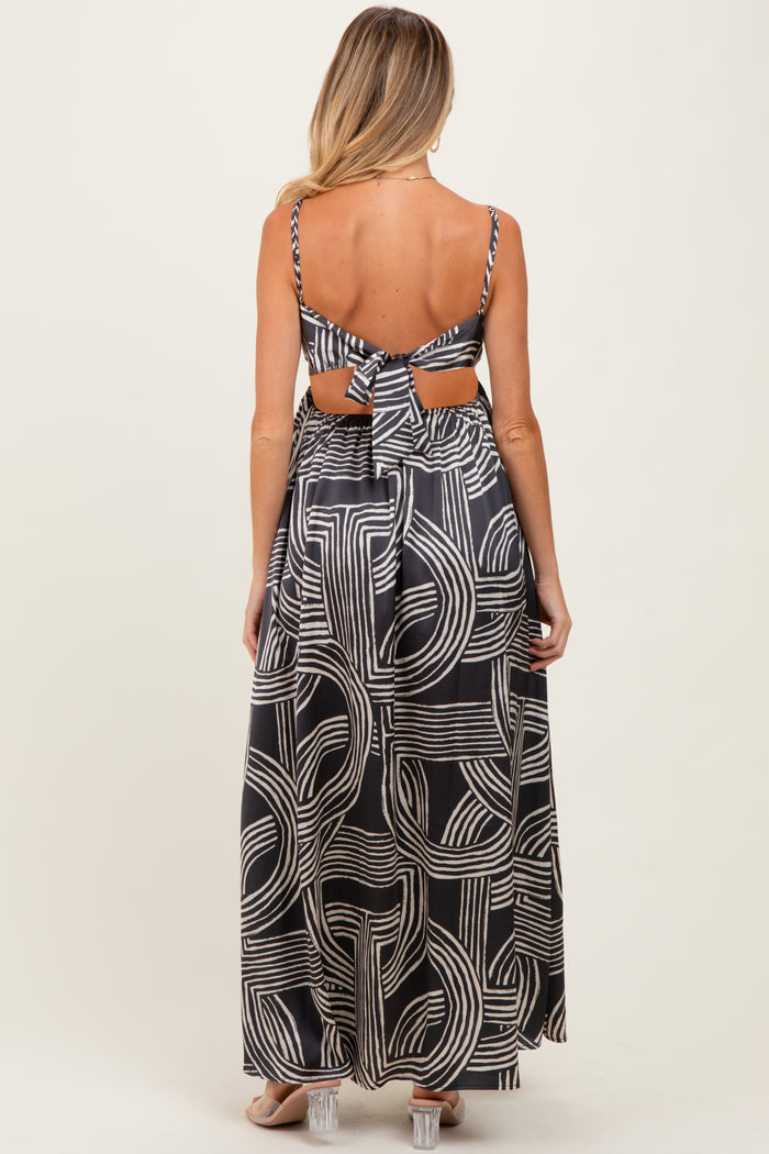 woman wearing a black and white patterned maternity maxi dress with an open back and tie details