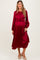 woman wearing a burgundy maternity pleated dress with ruffle details and a visible baby bump