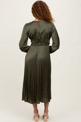 woman wearing a long olive green pleated satin dress with a fitted waist and long sleeves, shown from the back