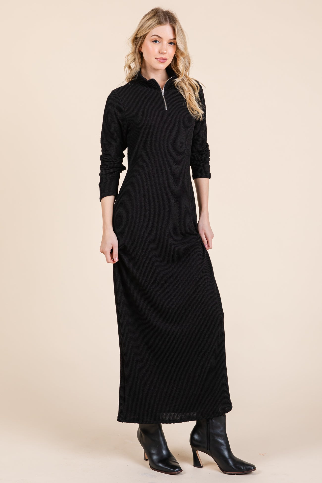 woman wearing a black ribbed long sleeve maxi dress with a zippered neckline and black ankle boots