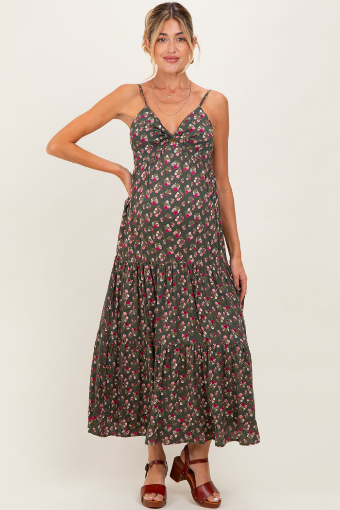 woman wearing a dark floral maternity maxi dress with a ruffled hem and thin straps, showcasing a baby bump