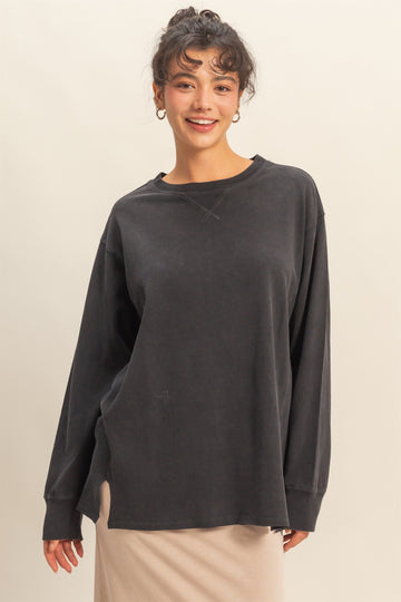 woman wearing a dark gray oversized long sleeve top with a relaxed fit and round neckline