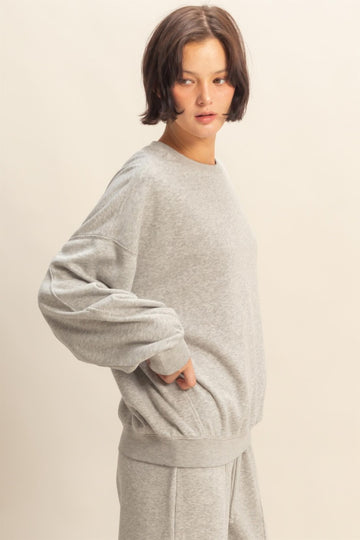woman wearing a grey oversized sweatshirt with long sleeves and a relaxed fit