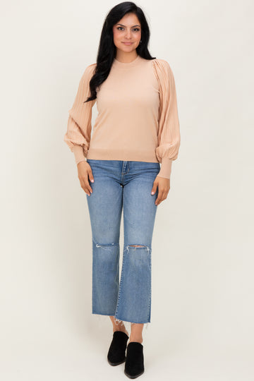 woman wearing a beige ribbed long sleeve top with puffed sleeves and blue cropped jeans with frayed hems