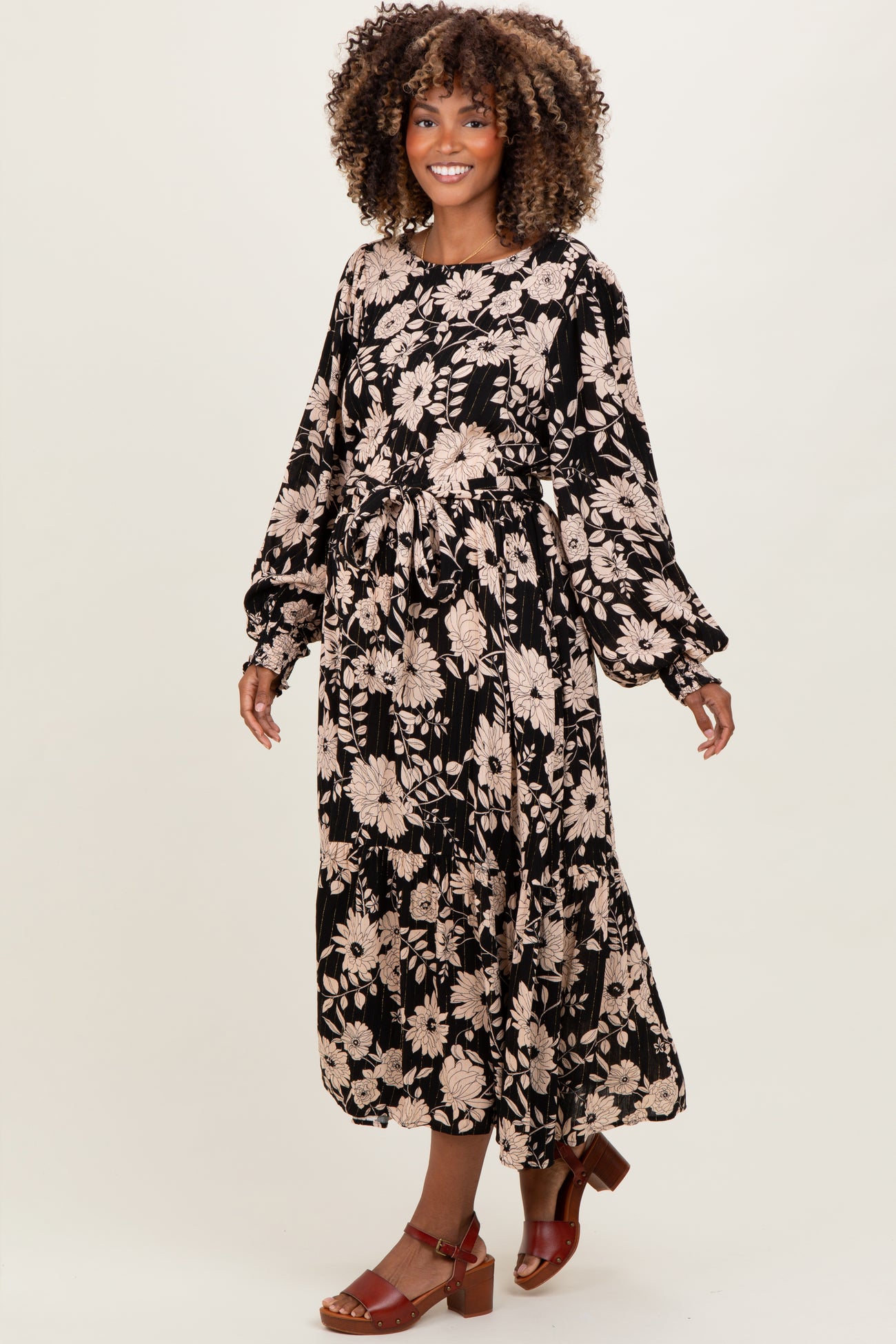woman wearing a black floral maternity maxi dress with long sleeves and a tiered skirt, showcasing a baby bump