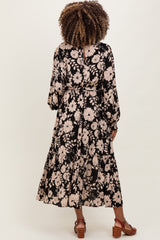 woman wearing a black floral maternity dress with long sleeves and tiered hem viewed from the back