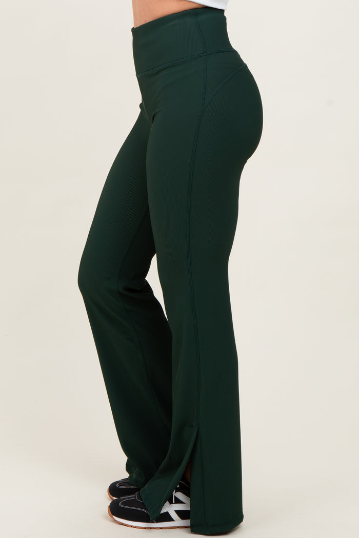 woman wearing high-waisted dark green flared workout pants with side slits and black athletic shoes