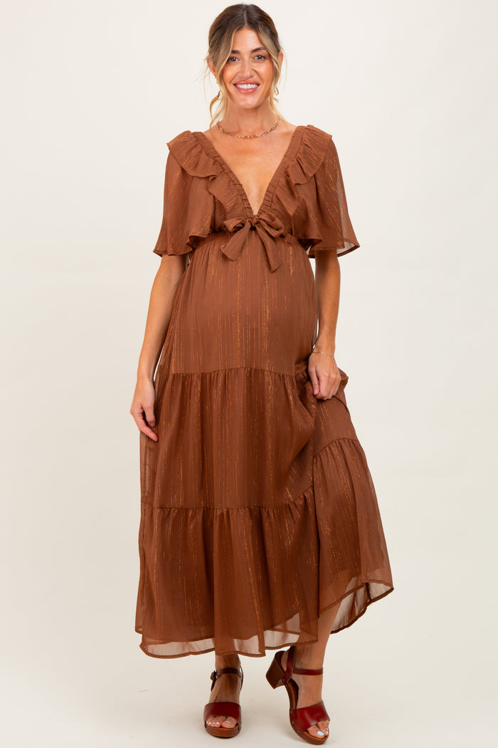 woman wearing a rust-colored tiered maternity dress with ruffled sleeves and a knotted front, showing her baby bump