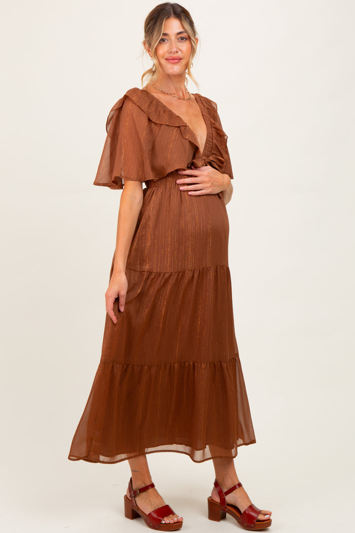 woman wearing a rust-colored maternity dress with ruffle sleeves and a tiered skirt, showcasing her baby bump