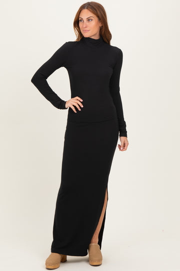 woman wearing a black long sleeve turtleneck maxi dress with a side slit and standing in a relaxed pose