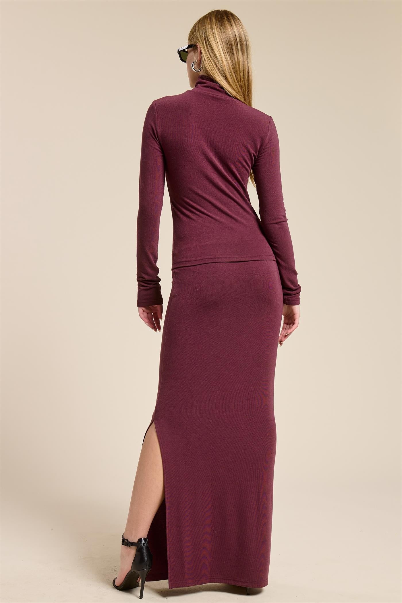 woman wearing a burgundy long sleeve fitted maxi dress with a side slit and turtleneck from the back