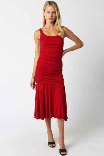 woman wearing a red fitted midi dress with ruched detailing and a flared hem, standing in a relaxed pose