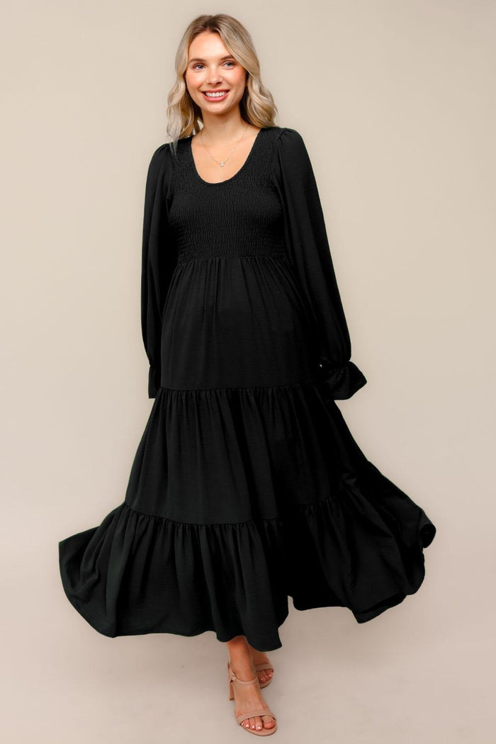 woman wearing a black long sleeve tiered maxi dress with a smocked bodice and flowy skirt