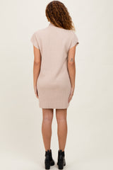 woman wearing a beige ribbed short sleeve dress, standing with her back to the camera