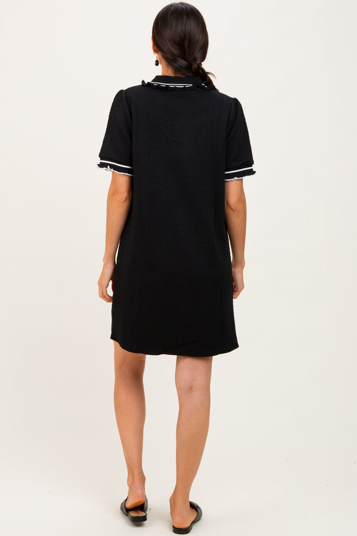 woman wearing a black short sleeve dress with white trim, viewed from the back