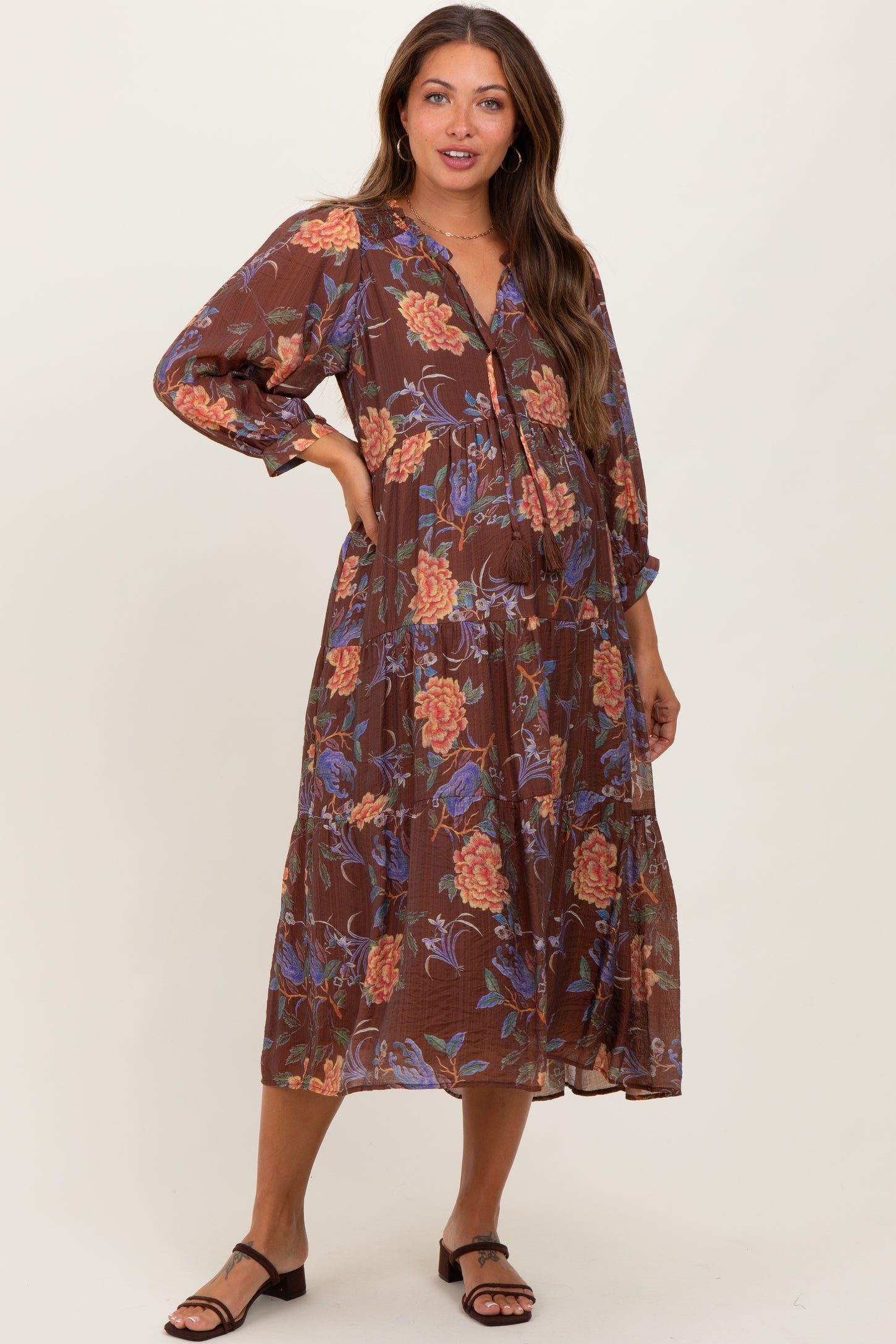 woman wearing a brown floral print maternity dress with long sleeves and a drawstring waist, showcasing her baby bump