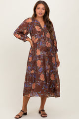 woman wearing a brown floral print maternity dress with long sleeves and a drawstring waist, showcasing her baby bump