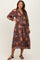 woman wearing a brown floral print maternity dress with long sleeves and a drawstring waist, showcasing her baby bump