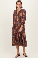 woman wearing a brown floral maxi dress with a tiered skirt and long sleeves, posing with a smile
