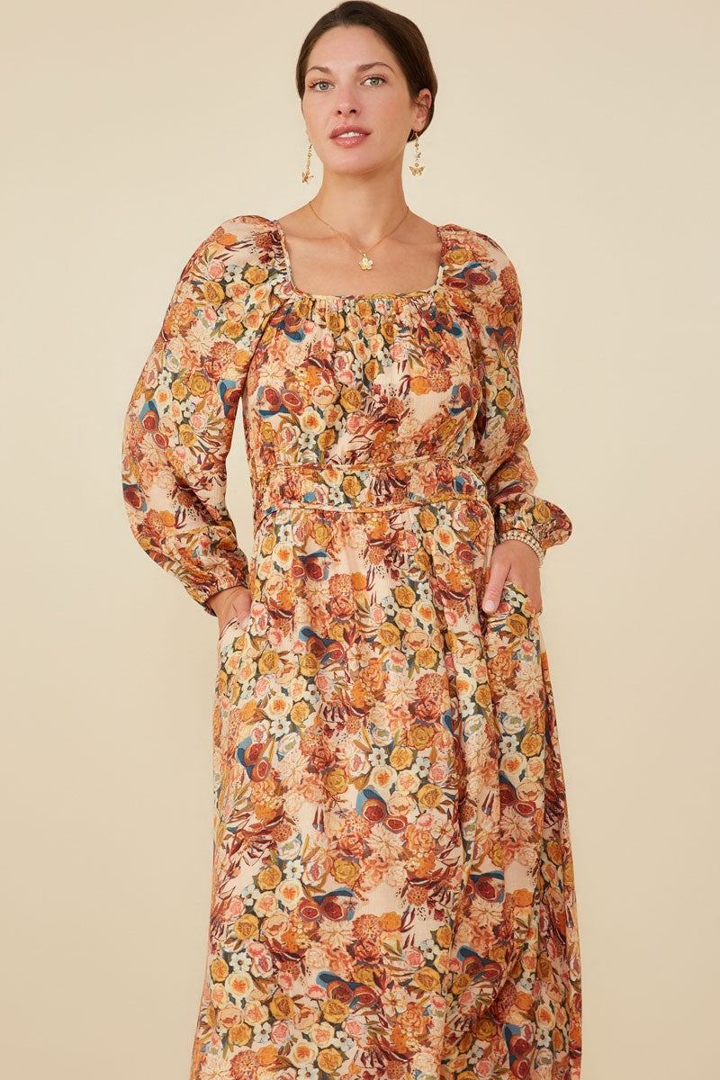 woman wearing a floral maxi dress with puff sleeves, square neckline, and an elastic waist with pockets