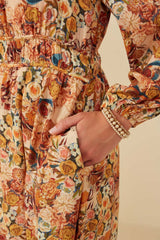 woman wearing a floral patterned midi dress with elastic waist and pockets, holding her hand in a pocket